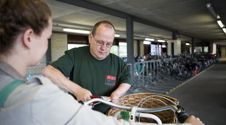 Werknemer controleert iets aan een fiets van een klant