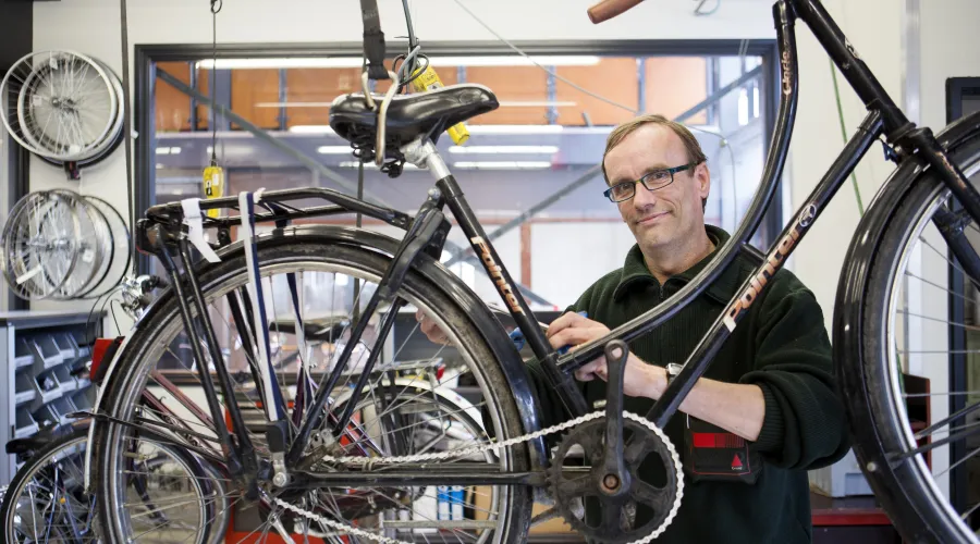 man sleutelt aan fiets