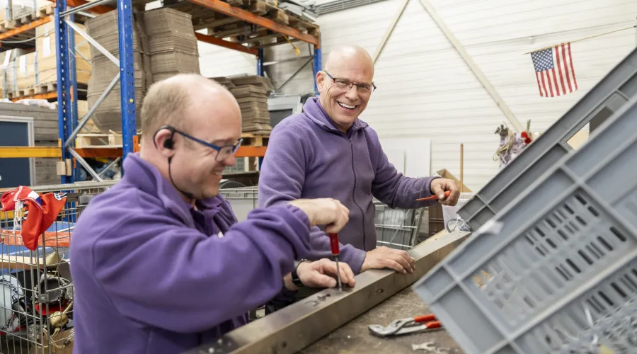 Twee mannen halen schroeven uit een balk bij Het Goed